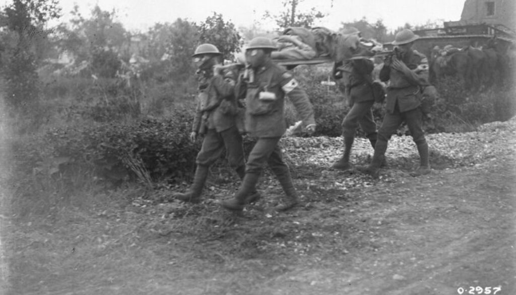 46_Canadians wearing gas masks bringing in wounded. Battle of Amiens. August, 1918.
